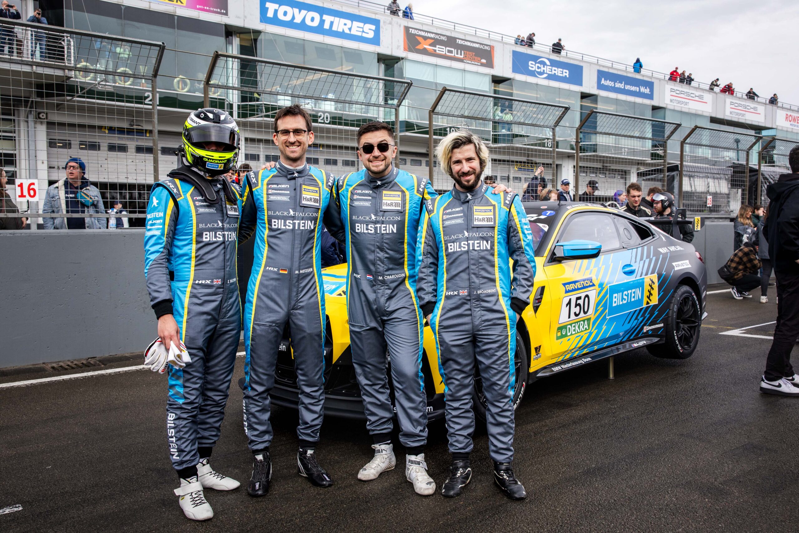 Team photo of the BILSTEIN Racing Team standing in front of the Race Car at the Nürgburgring.